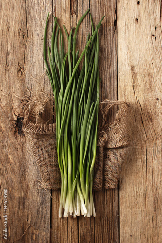  Green onion in burlap on a wooden table
