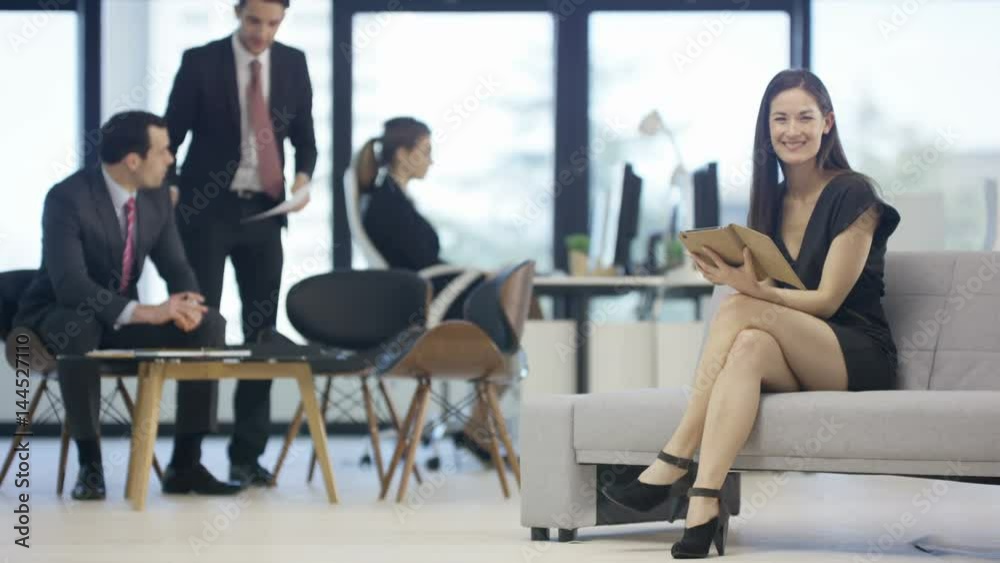 Portrait smiling businesswoman in office with colleagues working in background Portrait smiling businesswoman in office with colleagues working in background