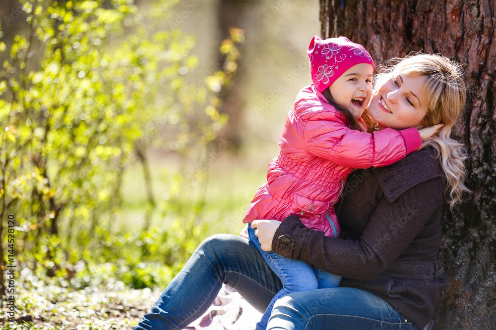 father and daughter sitting on a tree and laughing in the summer garden, happy family father and daughter sitting on a tree and laughing in the summer garden, happy family