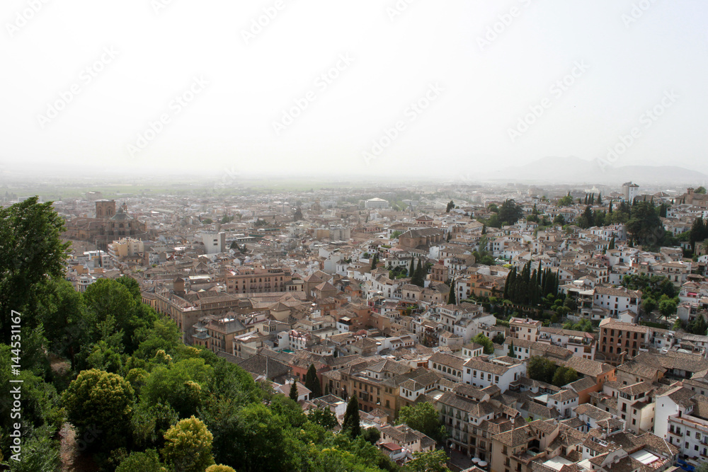 Spain. Granada.View of town with red roofs on white sky background, horizontal view.