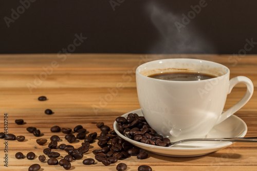 Coffee cup and coffee beans on wood table blurry background