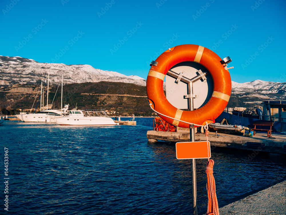 Lifebuoy in the marina for yachts. Red circle on the boat dock. Porto Montenegro, Montenegro.