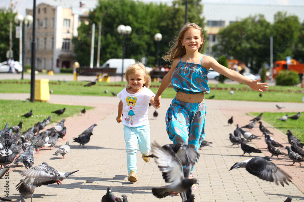 Young happy girl runs through a flock of pigeons on the square Young happy girl runs through a flock of pigeons on the square