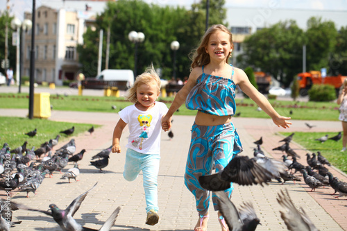 Happy little girl feeding doves in the city street