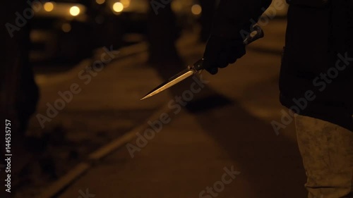 A knife in a hand of a woman. Night street slow motion