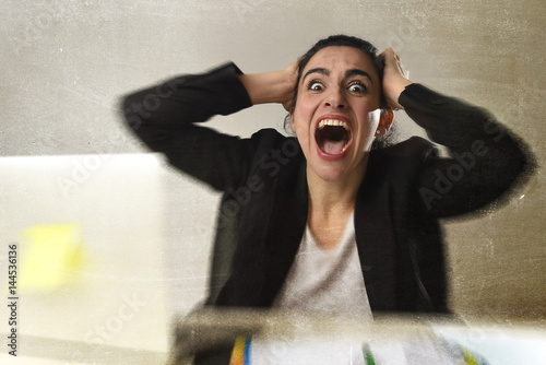 woman in business suit working in stress screaming desperate overwhelmed and overworked photo