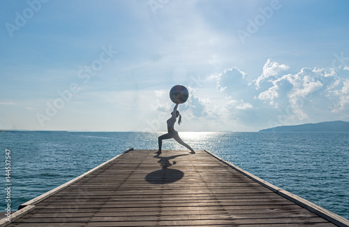 Yoga ball, pilates ball young woman in the beach sunrise background..