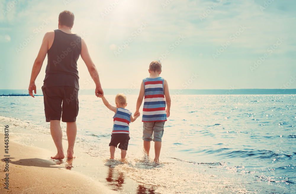 Father and sons walking at the beach at sea
