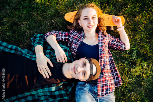 Hipster friends with skateboard lying on back smiling. photo