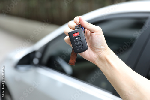 hand holding car key with car background