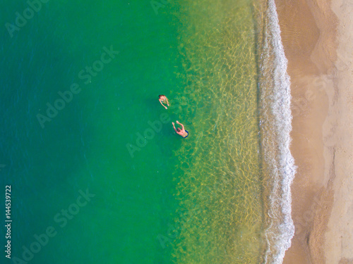 Man and woman sunbathing and swimming on the shore of the turquoise sea