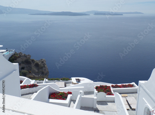 Stunning View of Blue Aegean Sea and White Terrace with Red Flowers, Santorini Island of Greece 