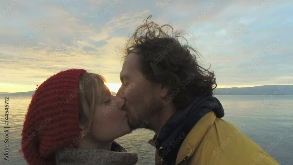 Couple kissing at sunset on at seaside with beautiful clouds Couple kissing at sunset on at seaside with beautiful clouds