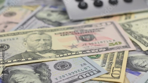 Dolly shot, focus on dollars, calculator lying on the table.