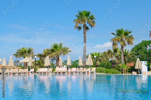 Fototapeta Naklejka Na Ścianę i Meble -  outdoor swimming pool, palm trees and a cozy area for sunbathing