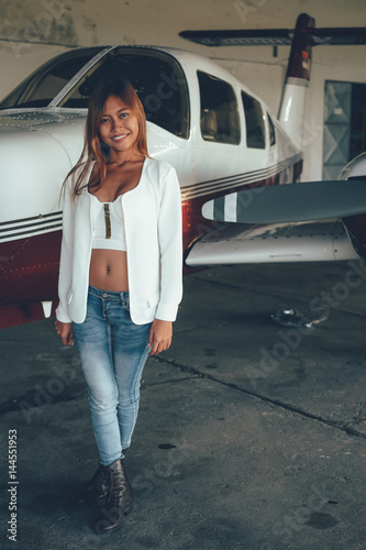 Beautiful female portrait in the airplane hangar, with modern aircraft