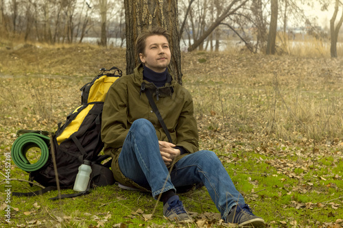  Active people. Outdoors. Traveler. Tourist. Sitting guy. A man with a backpack. Near a tree.