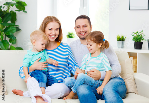 Happy family laughing and hugging at home on sofa