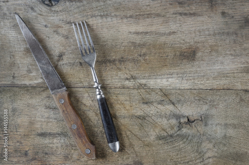 Old fork and knife on wooden board