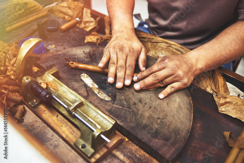 Closeup of hands making cigar from tobacco leaves. Traditional manufacture of cigars. Dominican Republic photo