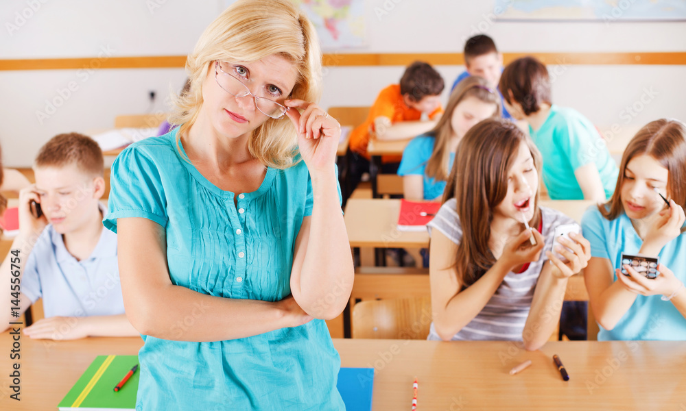 Teacher in classroom, pupils behind her are not listening to her. Teacher in classroom, pupils behind her are not listening to her.