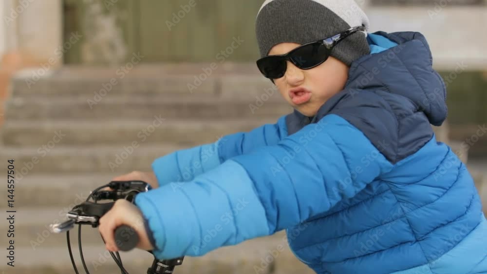 A boy wearing sunglasses sits on a bicycle.Full hd video A boy wearing sunglasses sits on a bicycle.Full hd video