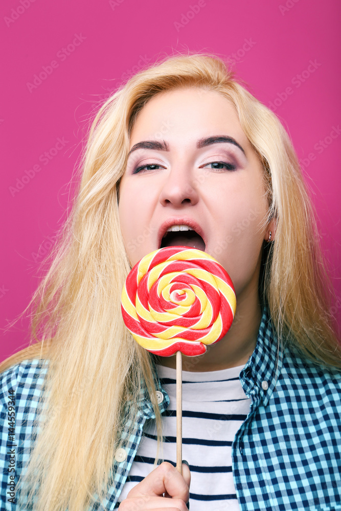 Young beautiful woman with lollipop on pink background