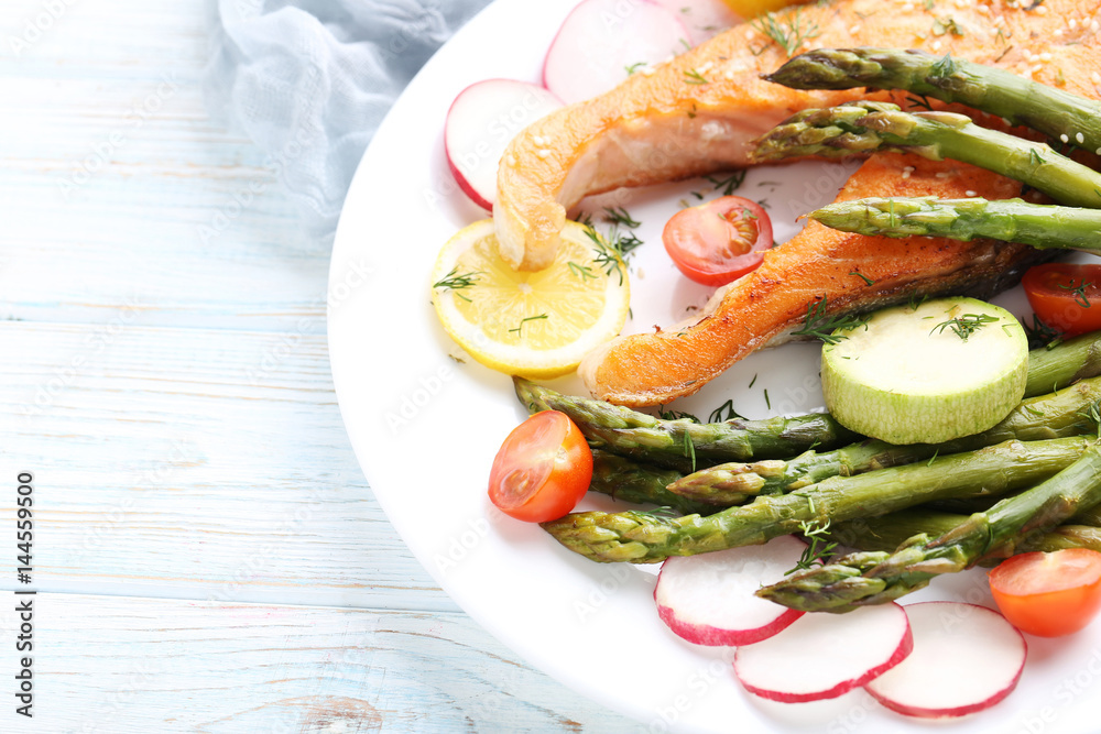Steak of salmon with asparagus and vegetables on white plate Steak of salmon with asparagus and vegetables on white plate