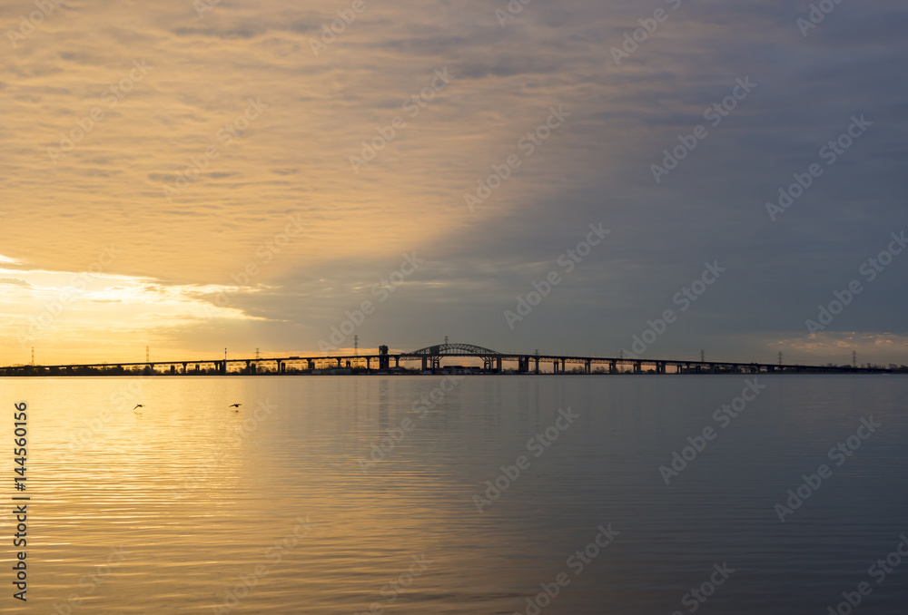 Peaceful blue and golden colorful sunrise over Skyway bridge and calm lake waters, dramatic sky and clouds