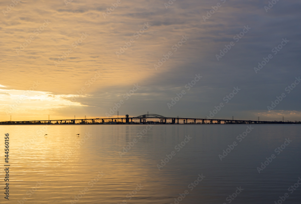 Peaceful blue and golden colorful sunrise over Skyway bridge and calm lake waters, dramatic sky and clouds Peaceful blue and golden colorful sunrise over Skyway bridge and calm lake waters, dramatic sky and clouds