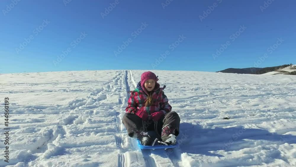 Little girl descending hill sledge on snowly hill Little girl descending hill sledge on snowly hill