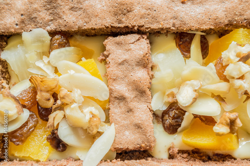 Home made brown piece of cake with dried fruits and nuts on top photo