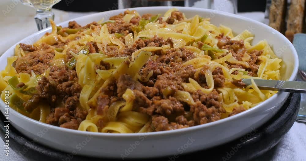 Sprinkling black pepper over delicious steamy fettuccine in bolognese sauce