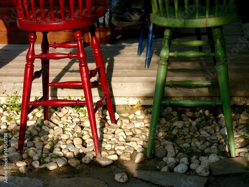 Bunte Barstühle in Rot und Grün aus Holz auf Kieselsteinen an einer Bar im Sommer bei Sonnenschein in der Altstadt von Alacati bei Cesme am Ägäischen Meer in der Provinz Izmir in der Türkei photo