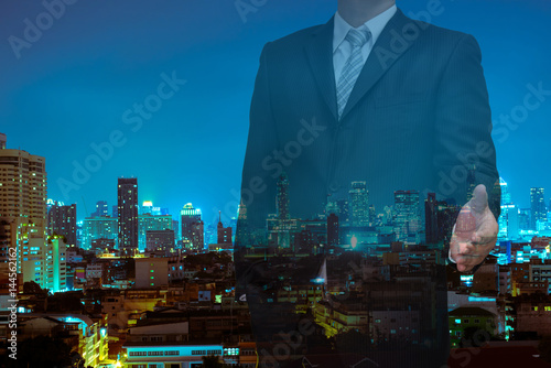 Double exposure of business with welcome hand and night modern city building background