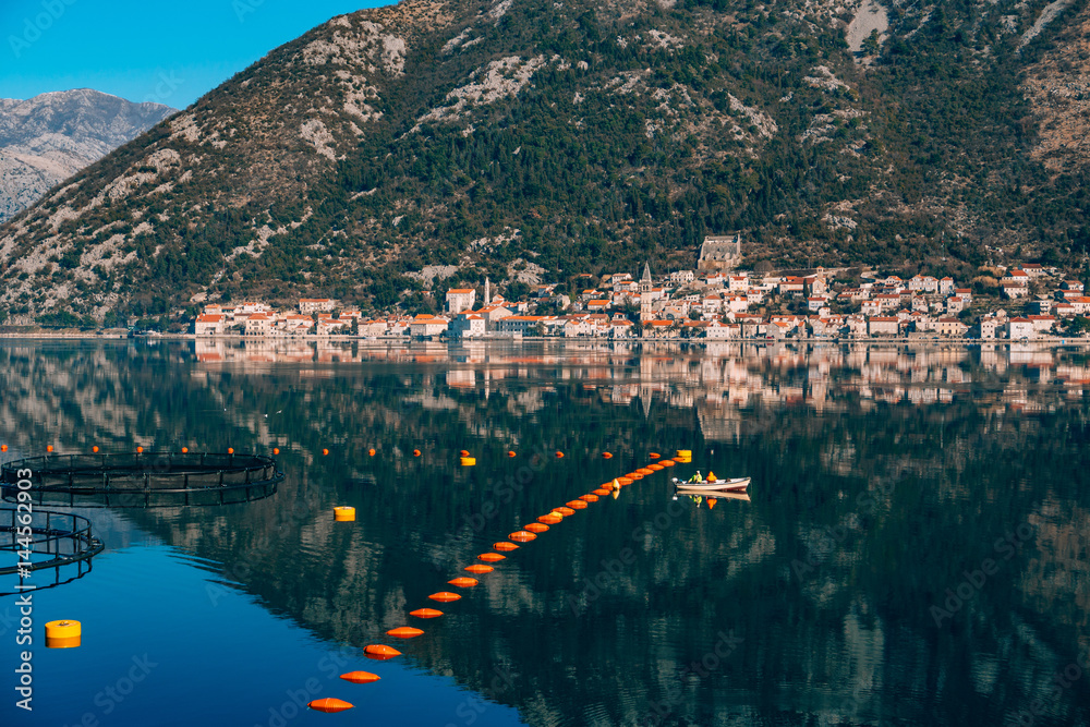 Fishermen in a boat are fishing. Kotor Bay, a view of the city of Perast and the island of Gospa od Skrpela, Montenegro.