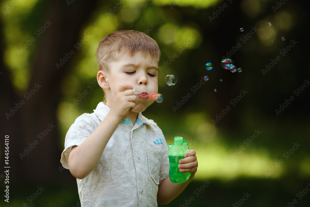 boy inflates bubbles in summer park boy inflates bubbles in summer park