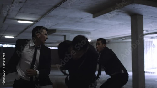 Asian gangster fighting in dark parking lot with members of a rival gang photo