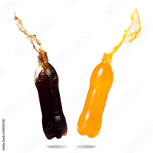 Orange juice and cola splash out of bottle on white background.