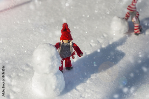 Two wooden dolls on white snow