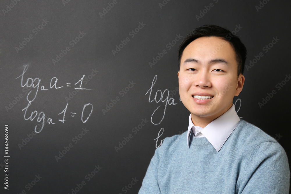 Handsome Asian teacher on blackboard background Handsome Asian teacher on blackboard background