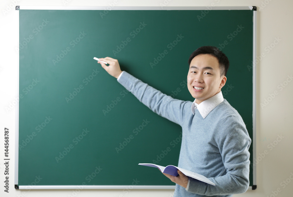 Handsome young Asian teacher writing on blackboard Handsome young Asian teacher writing on blackboard