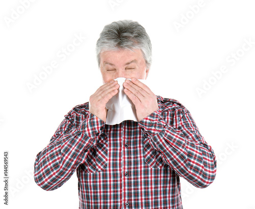 Senior man blowing nose on ...