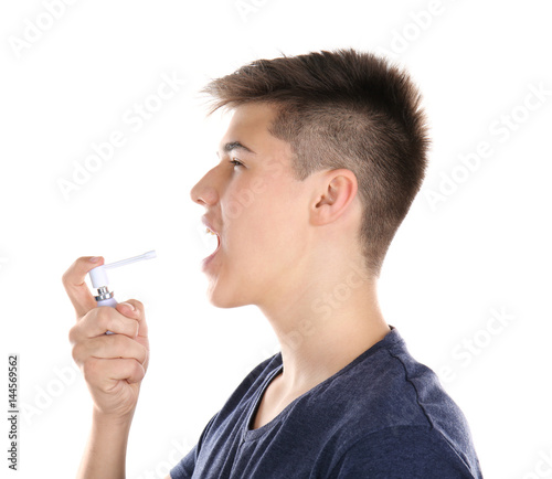 Sick young man using throat spray on white background