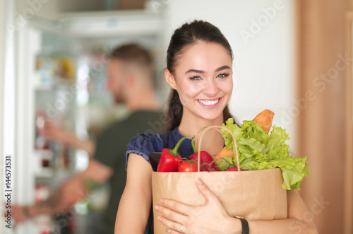 Young couple in the kitchen , woman with a bag of groceries shopping photo