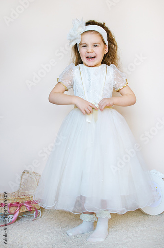 cute girl laughs in a pink princess dress with a bow