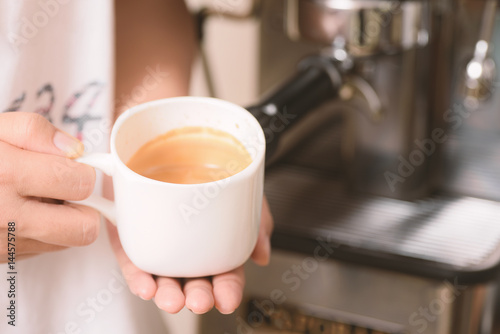 Barista holding cup of coffee that making from espresso machine
