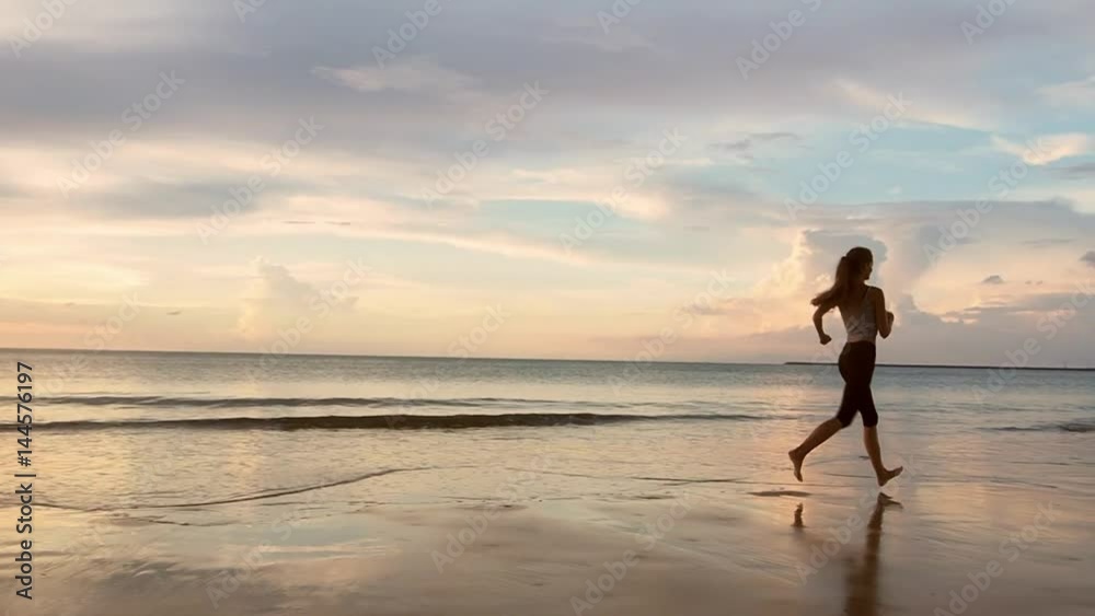 Woman Runs on a Sandy Beach at Sunrise