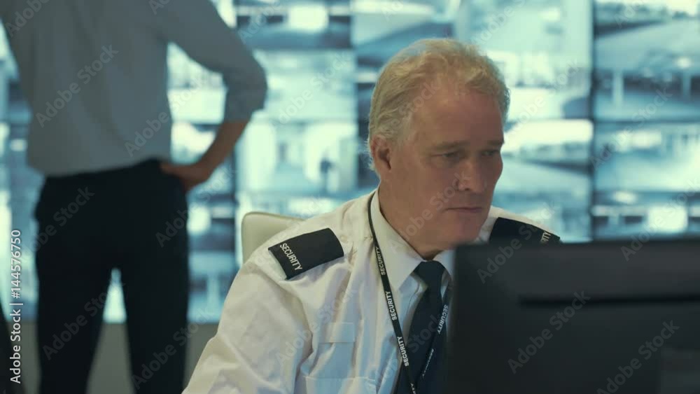 Security officer alone in observation control room does a little dance while no-one's watching. Security officer alone in observation control room does a little dance while no-one's watching.