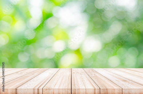 Empty wooden table top with blurred natural abstract background.